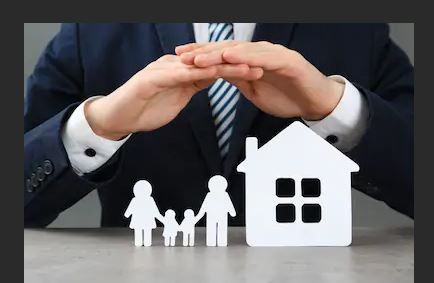Hands protect a cut-out family and house, symbolizing insurance and security.